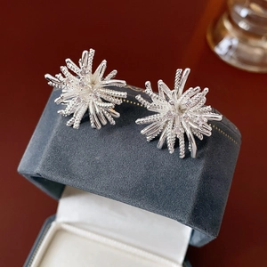 Detailed macro view of silver firework earrings with white zircon on blue velvet