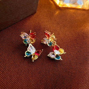 Macro view of colorful zircon butterfly earring set with gold plated metal on brown texture