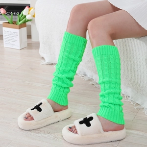 Detail of neon green cable knit leg warmers showing thick texture and ribbed cuffs