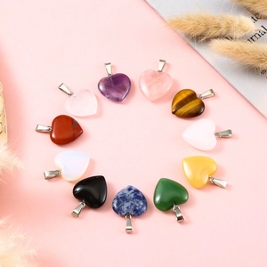 Flat lay of 12 natural crystal heart pendants in amethyst and quartz on pink backdrop
