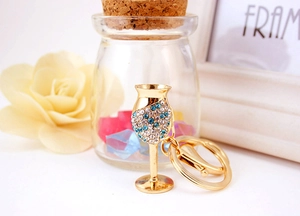 Close-up of golden wine glass keychain with blue and white crystals on a soft background