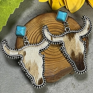 Dettaglio degli orecchini western con turchese e pendente a forma di teschio di toro