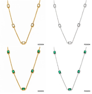 Detail view of gold and silver zircon necklaces featuring white and emerald green stones