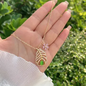 Dettaglio della collana a foglia in oro 18K con gemma verde e piccolo ciondolo a fiore rosa