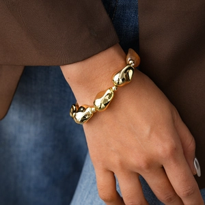 Detailed view of irregular golden acrylic beaded bracelet with mirror-like metallic finish