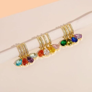 Detail of colorful teardrop zircon earrings hanging on a display rod in gold finish