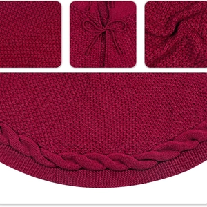 Dark red knitted Christmas tree skirt with decorative bow and textured crochet borders