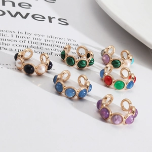 Gros plan de boucles d'oreilles ear cuff dorées avec malachite et pierres naturelles