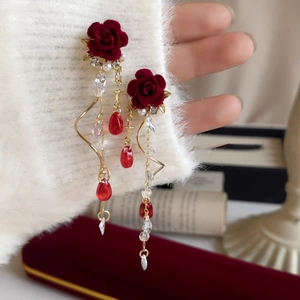 Close-up of vintage red velvet rose earrings with crystal tassels and gold chains