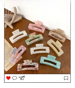 Lot de neuf grandes pinces à cheveux en acétate aux couleurs marbrées sur bois