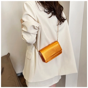 Chic metallic orange chain bag shown on a white suit jacket for a stylish daily look