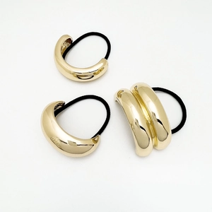 Detail shot of three minimalist gold alloy ponytail holders with polished mirror finish