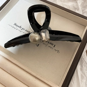 Detail of elegant black hair claw with ivory pearl and faceted crystal accent