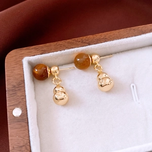 Detail view of gold gourd earrings with brown beads in a premium jewelry display box