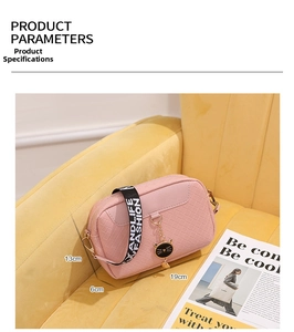 Pink woven crossbody bag with cat charm and strap measuring 19cm by 13cm by 6cm