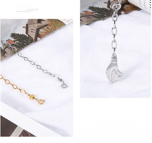 Détail du collier avec pendentif geste de la main cœur en finitions or et argent