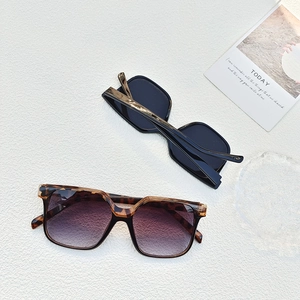 Detail view of square tortoiseshell and black sunglasses frames on a minimalist white surface