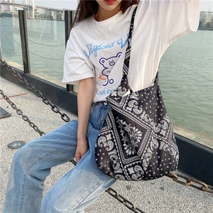 Outdoor model shot of a large canvas crossbody bag with white paisley print on black fabric