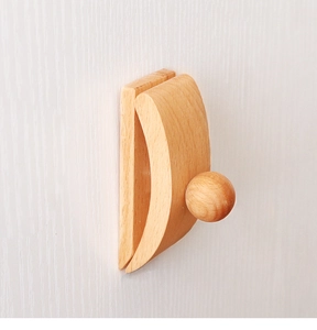 Détail d'un clip mural en bois pour courtepointe avec grain naturel sur mur gris