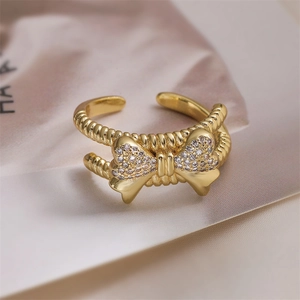 Dettaglio ravvicinato di un anello a fiocco dorato con pavé di zirconi e texture a spirale