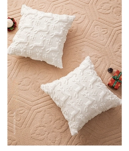 Close-up of two white Christmas pillow covers with embroidered reindeer and snowflake patterns