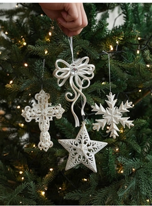 Detailed close-up of white glittery cross and star ornaments hanging on a Christmas tree
