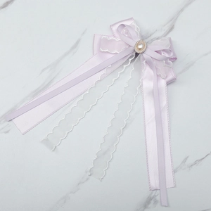 Detailed view of a purple satin bow hairclip with lace ribbons and a pearl rhinestone center