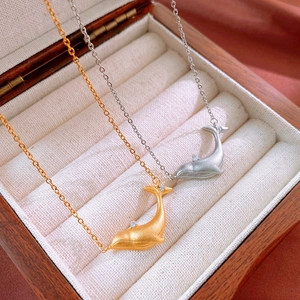 Elegant gold and silver whale necklaces with zircon on white velvet in a wooden box