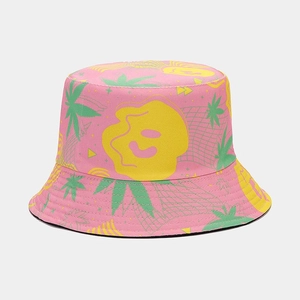 Close-up of pink canvas bucket hat featuring green leaf and yellow smiley face patterns