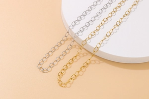 Close-up of gold and silver textured oval link chains on a white round display