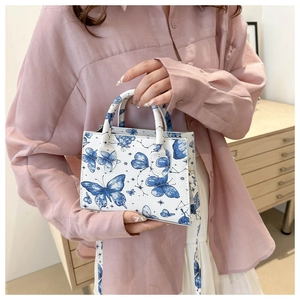 Detail of white shoulder bag with blue butterfly print and round top handles