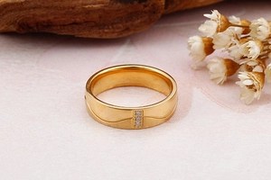 Vue détaillée d'une bague large en titane doré avec trois zircons sur fond texturé