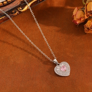 Gros plan du collier cœur avec pierre rose et bordure argentée sertie de cristaux