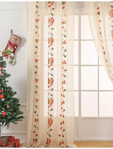 Close-up of Christmas bell embroidery on cream lace curtain with elegant scalloped edges
