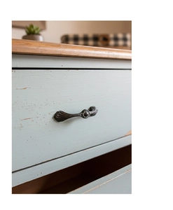 Close-up of vintage cast iron drawer handle with floral relief on distressed blue wood