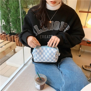 Detailed knit texture of light blue checkered makeup bag with metal zipper in soft natural light
