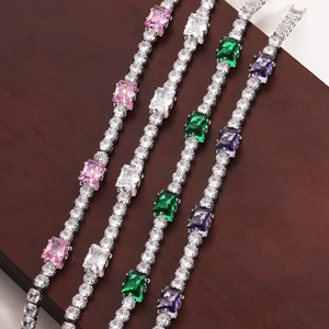 Close-up of silver tennis bracelets with emerald-cut crystals on wood surface
