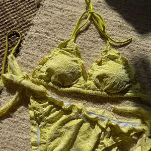 Detail view of yellow floral embroidery and delicate ruffles on bikini fabric texture