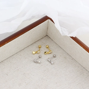 Close-up of gold and silver S925 heart screw back earrings with star charms in a wooden box