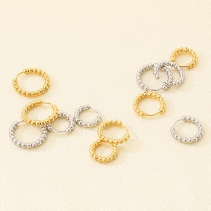 Close-up of gold and silver stainless steel hoop earrings with small beaded dots detail
