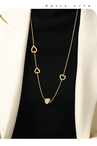 Detailed view of a gold double-layer heart pendant necklace on a black turtleneck sweater