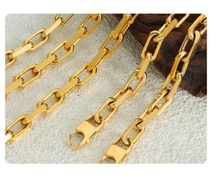 Macro shot of gold stainless steel Cuban chain necklace with secure lobster clasp on stone