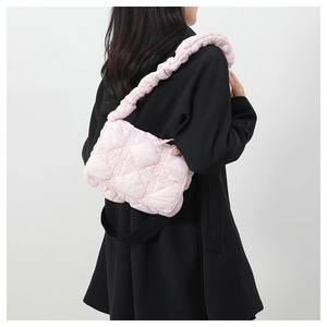 Detail of light pink quilted puffer bag with signature scrunchie handle on model