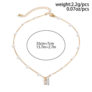 Detail of gold chain necklace with white imitation pearls and clear crystal pendant charm