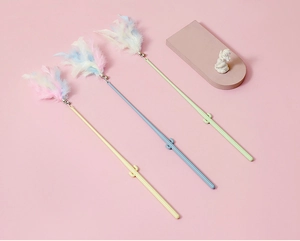 Close-up of three pastel cat teaser wands with natural feathers, bells and cactus decor