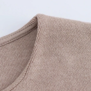 Primer plano de la textura de punto y costuras finas en una blusa color camello