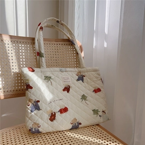 Close-up of quilted cotton tote bag featuring vintage bear prints and a woven label