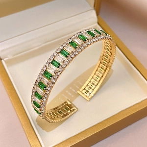 Detailed macro view of an emerald green gemstone bangle set in a luxury gold jewelry box