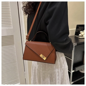 Detailed close-up of brown crocodile texture leather bag with a gold twist lock