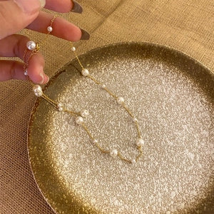 Elegant gold titanium steel necklace with white pearls displayed on a gold tray